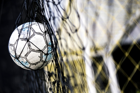 A soccer ball stuck on the net behind goal